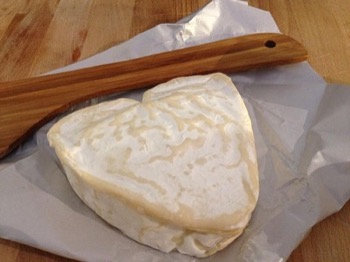 Neufchâtel on a wood surface with a wood utensil